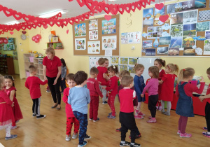 Grupa dzieci 4- letnich ubranych na czerwono, tańczących w kółeczkach
